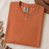 Just a t-shirt. Comfort Colors unisex garment-dyed heavyweight plain t-shirt with Radiant Art logo on right sleeve - Burnt Orange folded t-shirt mockup