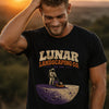 Man modeling black graphic t-shirt with Lunar Landscaping Co. EST. 1969 astronaut mowing moon lawn design in golden hour sunset outdoor setting