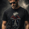 Man with curly brown hair, beard and sunglasses wearing black t-shirt featuring alligator in plaid shirt riding a bicycle graphic design
