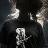 Woman with long flowing brown hair wearing black t-shirt featuring elephant playing bass guitar graphic design