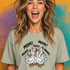 Woman with messy blonde hair laughing wearing sage green "MOM! MOM! MOM!" geese t-shirt with chaotic goose family graphic