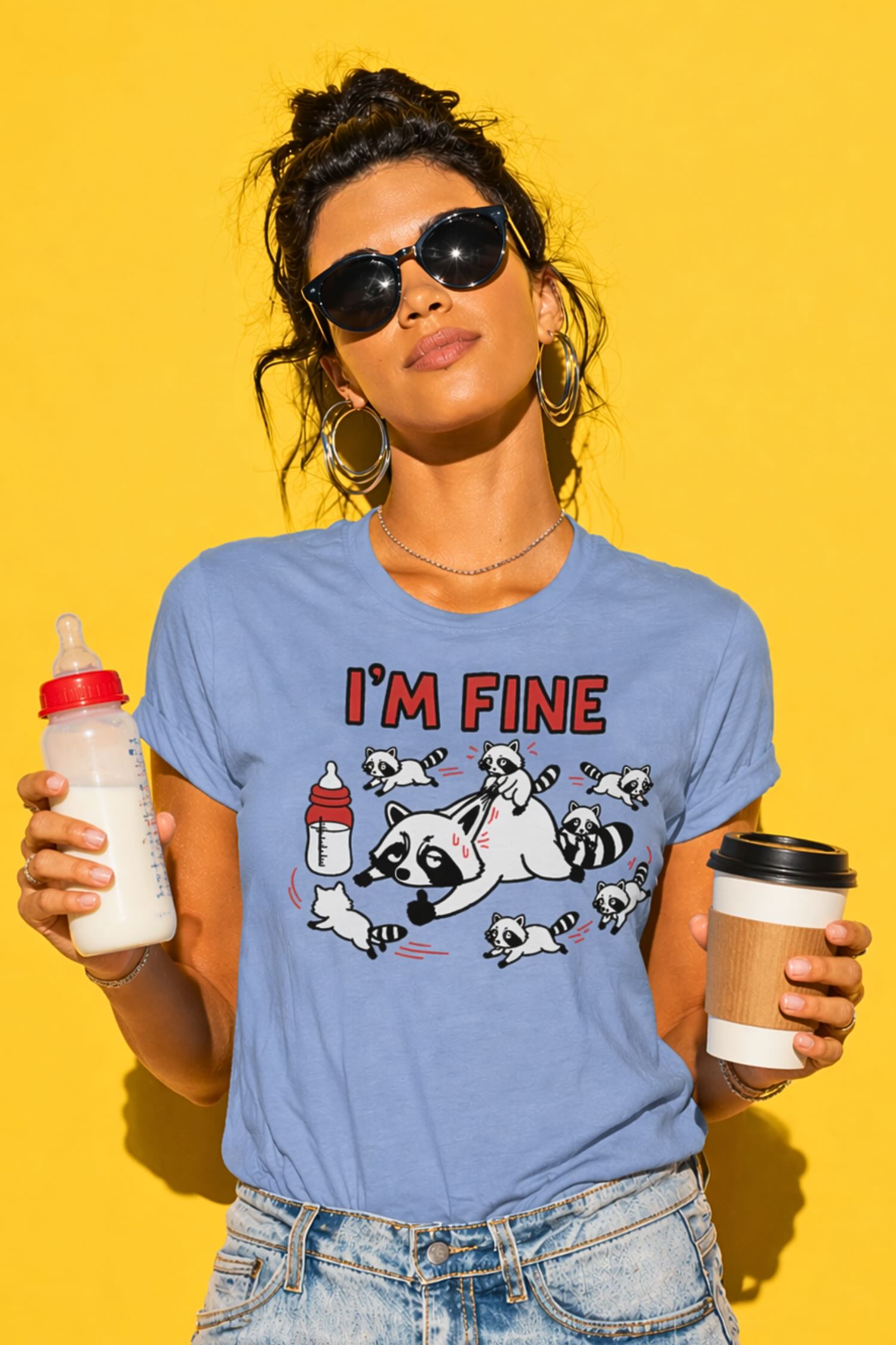 Woman with messy dark hair in bun and sunglasses wearing blue "I'm Fine" raccoon mom t-shirt with chaotic baby raccoons graphic